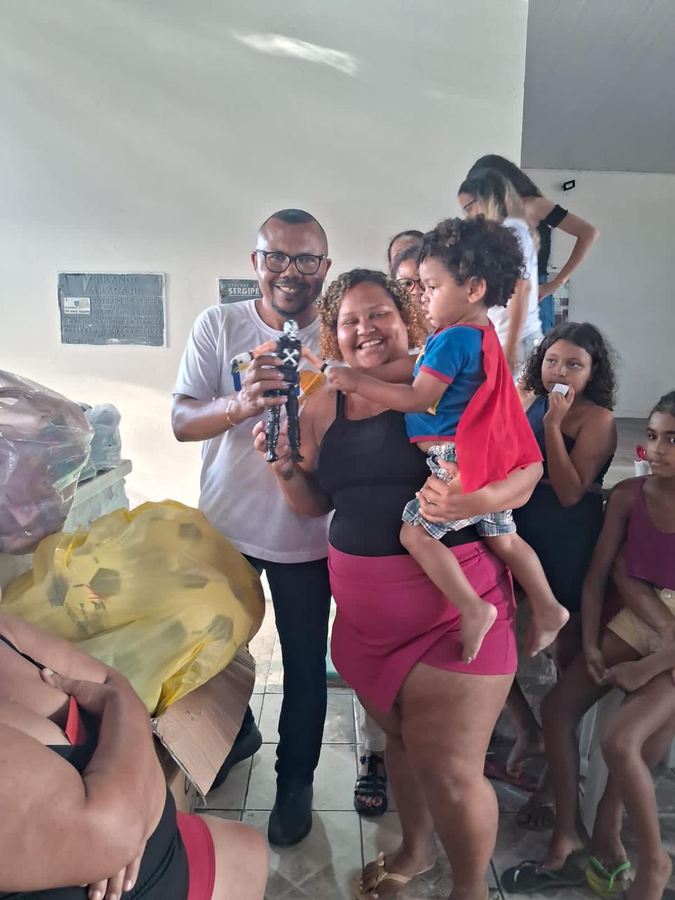 Vavá, mãe e criança com presente da campanha