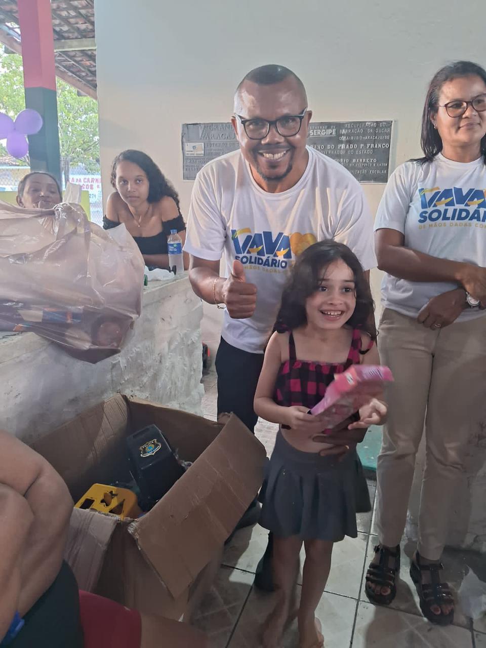 Criança mostra seu presente ao lado da equipe