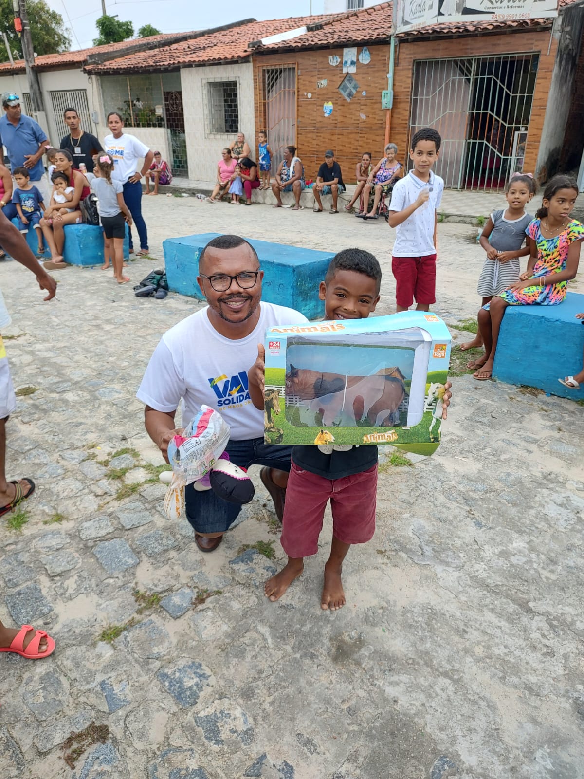 Vavá e uma criança mostrando brinquedos recebidos na ação